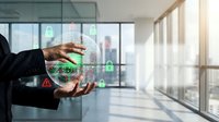 Businessman in dark suit holding glowing digital sphere with security icons and network symbols in modern office with city skyline view through windows.