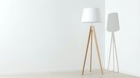 Wooden tripod floor lamp with white fabric shade and modern white standing lamp in minimalist interior space for home decor design projects.