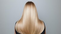 Straight blonde hair from back view on gray background showing smooth, glossy texture and professional salon styling result. For beauty and haircare advertising.