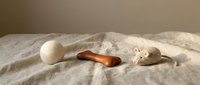 Minimalist pet toys arranged on linen fabric, featuring a wool felt ball, wooden bone, and knitted mouse toy in neutral tones.
