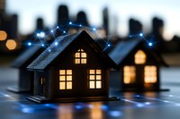 Smart home concept with glowing miniature houses connected by digital network lines against blurred city skyline background at dusk, showing modern technology integration.