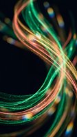 Abstract colorful light trails creating dynamic flowing curves with green orange yellow streaks against dark background for modern digital design.