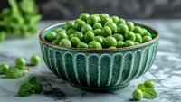 Fresh green peas in vintage ceramic turquoise bowl on marble background with mint leaves, healthy organic vegetables for cooking and nutrition.