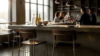 Modern bar counter with empty stools and blurred patrons socializing in background, suitable for hospitality, restaurant, and lifestyle design projects.