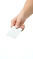 Female hand holding blank white business card isolated on white background for mockup design and branding presentations.