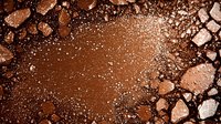 Crushed bronzer or cocoa powder makeup scattered and spilled creating abstract textured pattern with shimmering particles on dark background.