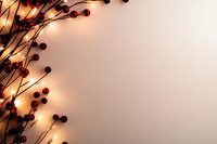 Glowing string lights intertwined with red winter berries create magical border on beige background, festive holiday mood for seasonal greeting cards and decor.