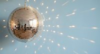 Sparkling disco ball casting golden light reflections against blue background creating festive party atmosphere for celebrations and nightlife events.