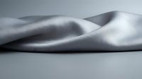 Smooth silver metallic fabric with flowing curves and soft shadows creating elegant waves and folds on neutral background for luxury design projects.