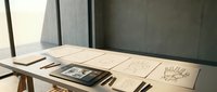 Modern minimalist workspace with wooden desk, notebooks, and natural lighting for creative professionals and office design concepts.