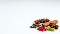 Aromatic spices collection with cinnamon sticks, star anise, cloves and cardamom pods isolated on white background for culinary and cooking projects.