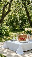 Elegant outdoor dining setup with white tablecloth, crystal glasses, fresh strawberries and flowers under blooming trees for romantic picnic or garden party.