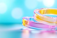 Colorful glass rings with iridescent reflections on turquoise background with bokeh effect, creating abstract minimalist composition for modern design projects.