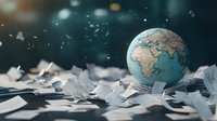 Globe model on scattered paper pieces with dramatic lighting and shallow depth of field, representing global business, education, or environmental concepts.