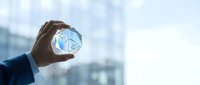 Businessman hand holding glowing digital earth globe with network connections against modern office building background for global business technology.