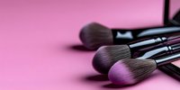 Professional makeup brushes with soft bristles arranged on pink background, selective focus creating artistic blur effect for cosmetic and beauty industry use.