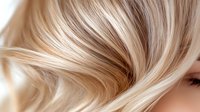 Luxurious blonde wavy hair close-up showing smooth, silky texture and highlights. Professional hairstyling and beauty treatment result with natural shine and movement.