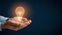 Businessman hand holding glowing light bulb against dark blue background, symbolizing innovation, creativity, and bright ideas for business solutions and success.