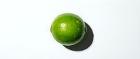 Fresh green lime with water droplets isolated on white background, suitable for food and beverage design projects.