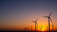 Wind turbines silhouetted against dramatic sunset sky creating renewable energy landscape for sustainable power generation and environmental concepts.