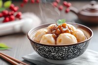Steaming hot rice balls in sweet brown sauce served in traditional Asian ceramic bowl with decorative pattern, garnished with mint leaf and cranberries.