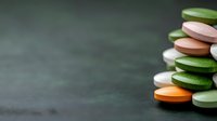 Colorful stacked medicine tablets and pills on dark background with copy space, pharmaceutical and healthcare concept for medical presentations.