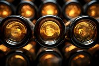 Empty brown glass beer bottles photographed from above showing bottoms with embossed logos glowing in warm light, creating artistic pattern.