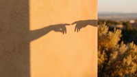 Silhouette of rifle with scope cast on warm golden wall during sunset, suitable for military, hunting, and security-related designs.