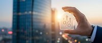 Businessman hand holding percentage symbol with city skyline at sunset representing financial growth, interest rates, and investment opportunities.