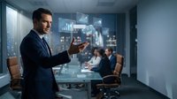 Professional businessman presenting data analytics on holographic display during corporate meeting in modern conference room.