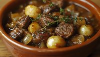 Hearty beef stew with tender meat chunks, pearl onions, and fresh herbs in rich brown gravy served in rustic terracotta bowl, close up view of homestyle comfort food.