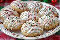 Festive sugar cookies with white icing drizzle and red and green sprinkles arranged on a decorative plate, perfect for holiday baking, Christmas celebrations, and seasonal dessert content.