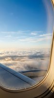 Aerial view from airplane window showing wing and vast cloudscape below during flight, perfect for travel and aviation concepts.