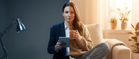 Professional businesswoman using tablet computer while sitting in modern office chair during golden hour lighting for corporate technology concepts.