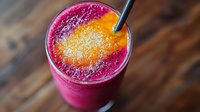 Vibrant pink and orange layered smoothie with chia seeds in glass on wooden table. Fresh tropical fruit drink with gradient effect and black straw.