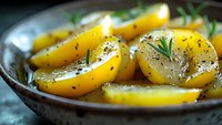 Roasted yellow potatoes with herbs and spices in rustic bowl, close-up view of homemade side dish for dinner or restaurant menu.