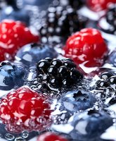Fresh mixed berries with water drops - raspberries, blackberries, and blueberries in macro photography showing juicy texture and natural freshness. Great for food packaging.