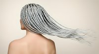 Rear view of person with long braided hair extensions flowing against neutral background, suitable for beauty and hair care marketing materials.