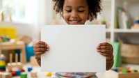 Young African American child with curly hair holding blank white paper in playroom, smiling while displaying artwork or announcement for educational, creative, or promotional use.