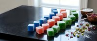 Colorful handmade soap bars in blue red green arranged on dark surface with natural ingredients and flower petals for organic skincare and beauty products.