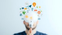 Creative business concept with light bulb and colorful innovation icons floating above hand, representing ideas, technology and digital transformation.