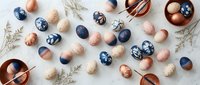 Elegant Easter eggs in navy blue and copper tones with decorative patterns scattered on white background. Holiday celebration and spring decoration concept.