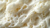 Creamy white foam texture with bubbles and organic patterns for skincare, cosmetic and spa design backgrounds.