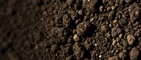 Closeup of rich brown soil texture with granular particles and natural shadows, suitable for agriculture, gardening, environmental, and landscaping projects.
