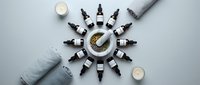 Natural skincare products arranged in circular pattern with essential oil bottles, candles and towels for spa wellness and aromatherapy treatments.