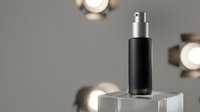 Black cosmetic spray bottle with silver pump on transparent cube podium against neutral background with soft lighting for skincare product display.