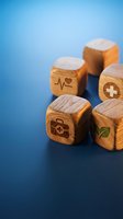Wooden cubes with healthcare symbols including heartbeat, cross, medical bag and leaf on blue background for wellness and medical concepts.