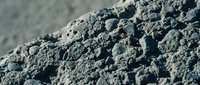 Close-up macro view of dark gray volcanic pumice stone texture with porous surface and natural holes for geology education and construction materials.
