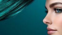 Young woman with turquoise hair and natural makeup in profile view against teal background, showing flawless skin, pink lips and long eyelashes. Fashion portrait.
