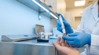 Medical professional in blue gloves holding test tube in modern laboratory for scientific research and analysis.